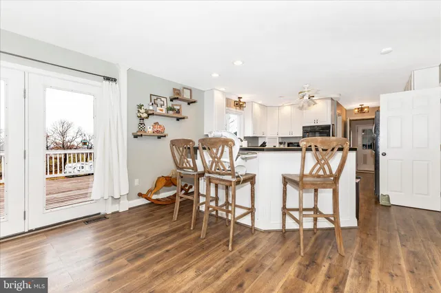 a kitchen with stainless steel appliances granite countertop a refrigerator a stove and white cabinets with wooden floor