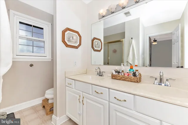 a bathroom with a sink a toilet a mirror a vanity a bathtub and shower