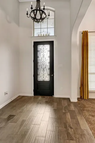 an empty room with wooden floor chandelier fan and windows