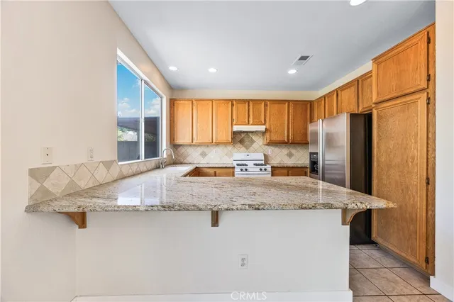 a kitchen with stainless steel appliances granite countertop a sink refrigerator and window