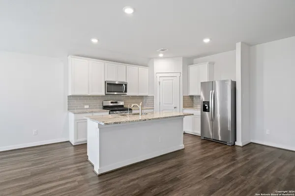 a kitchen with stainless steel appliances granite countertop a refrigerator stove top oven and sink