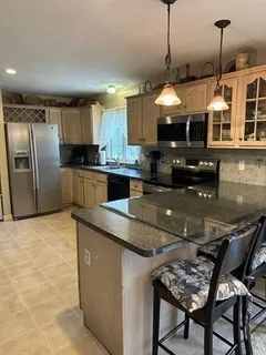 a kitchen with stainless steel appliances granite countertop a sink a stove and a wooden floors