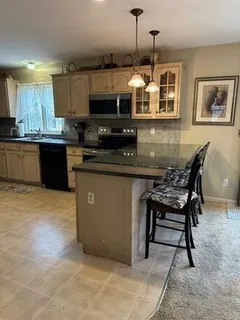 a kitchen with stainless steel appliances granite countertop a stove top oven a sink a dining table and chairs