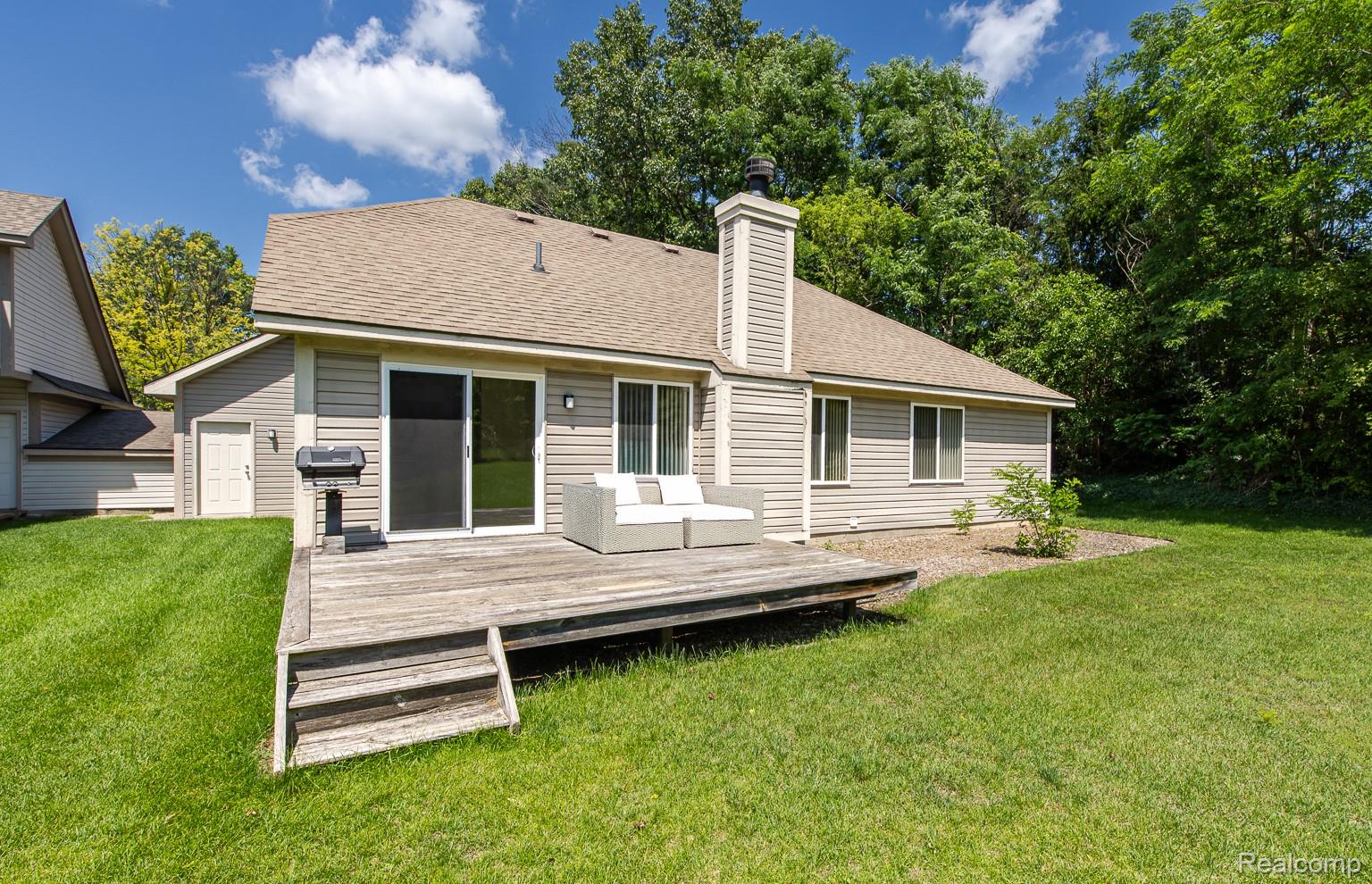 312 Reid Road Highland, MI 48357 - Photo 2 of 5 Rear exterior with a wooden deck featuring steps to the lawn