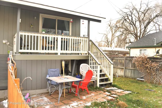 a view of a house with a wooden deck and furniture