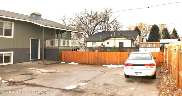 a view of a back yard of the house with a car parked