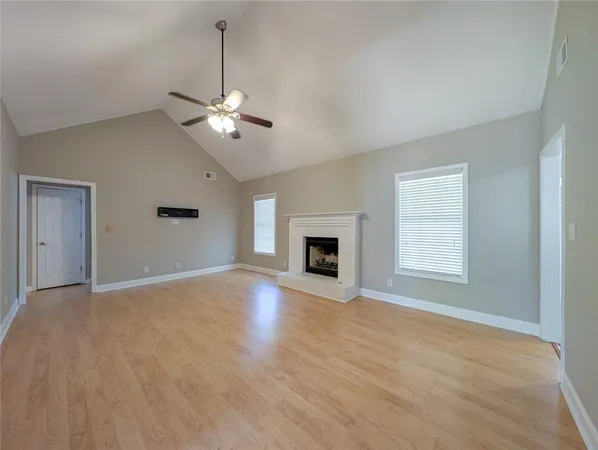 a view of an empty room with chandelier fan and a fireplace