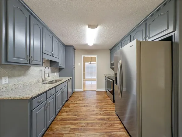 a kitchen with stainless steel appliances granite countertop a refrigerator a sink dishwasher a stove and a refrigerator