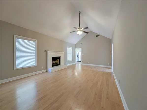 an empty room with wooden floor fireplace and windows