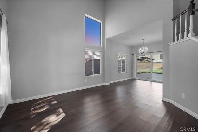 an empty room with wooden floor fire place and windows