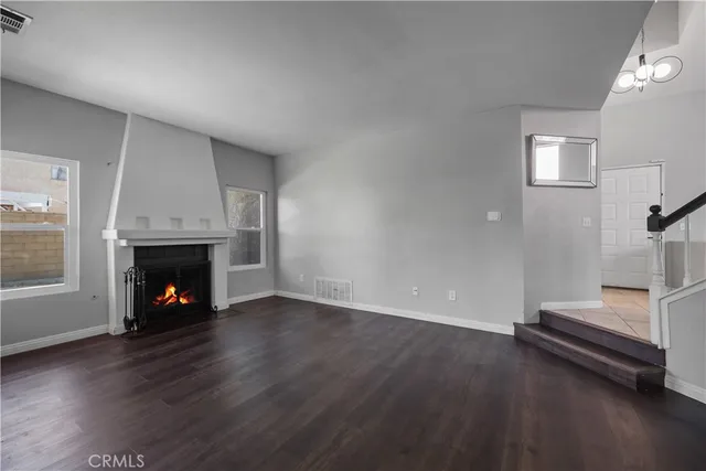 an empty room with wooden floor fire place and windows