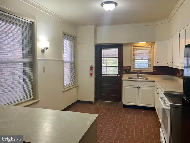 a kitchen with a sink a stove cabinets and wooden floor
