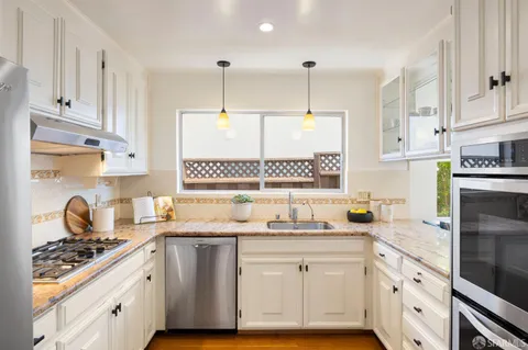 a kitchen with stainless steel appliances a sink stove and cabinets