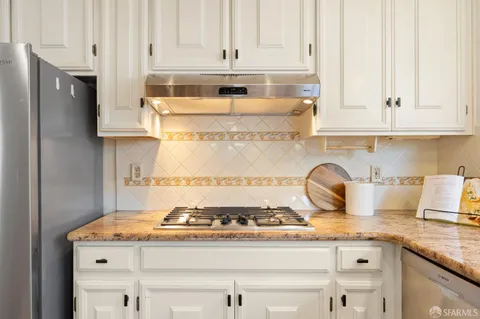 a kitchen with granite countertop a stove oven and white cabinets
