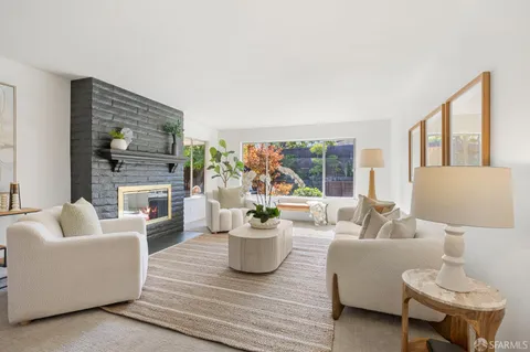 a living room with furniture a fireplace and a large window