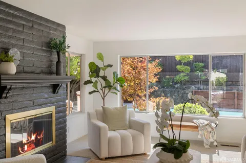 a living room with furniture a fireplace and a floor to ceiling window