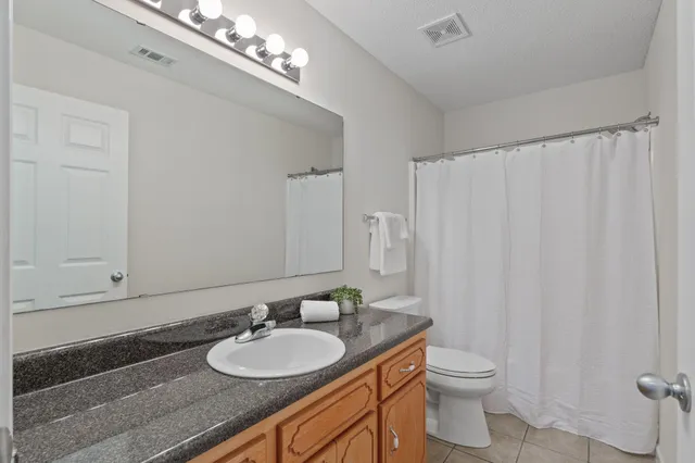 a bathroom with a granite countertop sink a toilet and a mirror