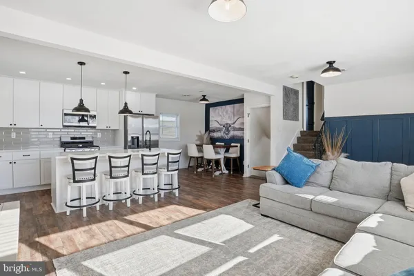 a living room with furniture kitchen view and a wooden floor