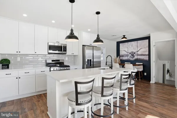 a kitchen with stainless steel appliances kitchen island granite countertop a stove a sink a dining table and chairs with wooden floor