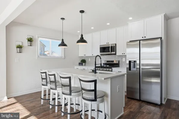 a kitchen with stainless steel appliances kitchen island a table chairs refrigerator and microwave