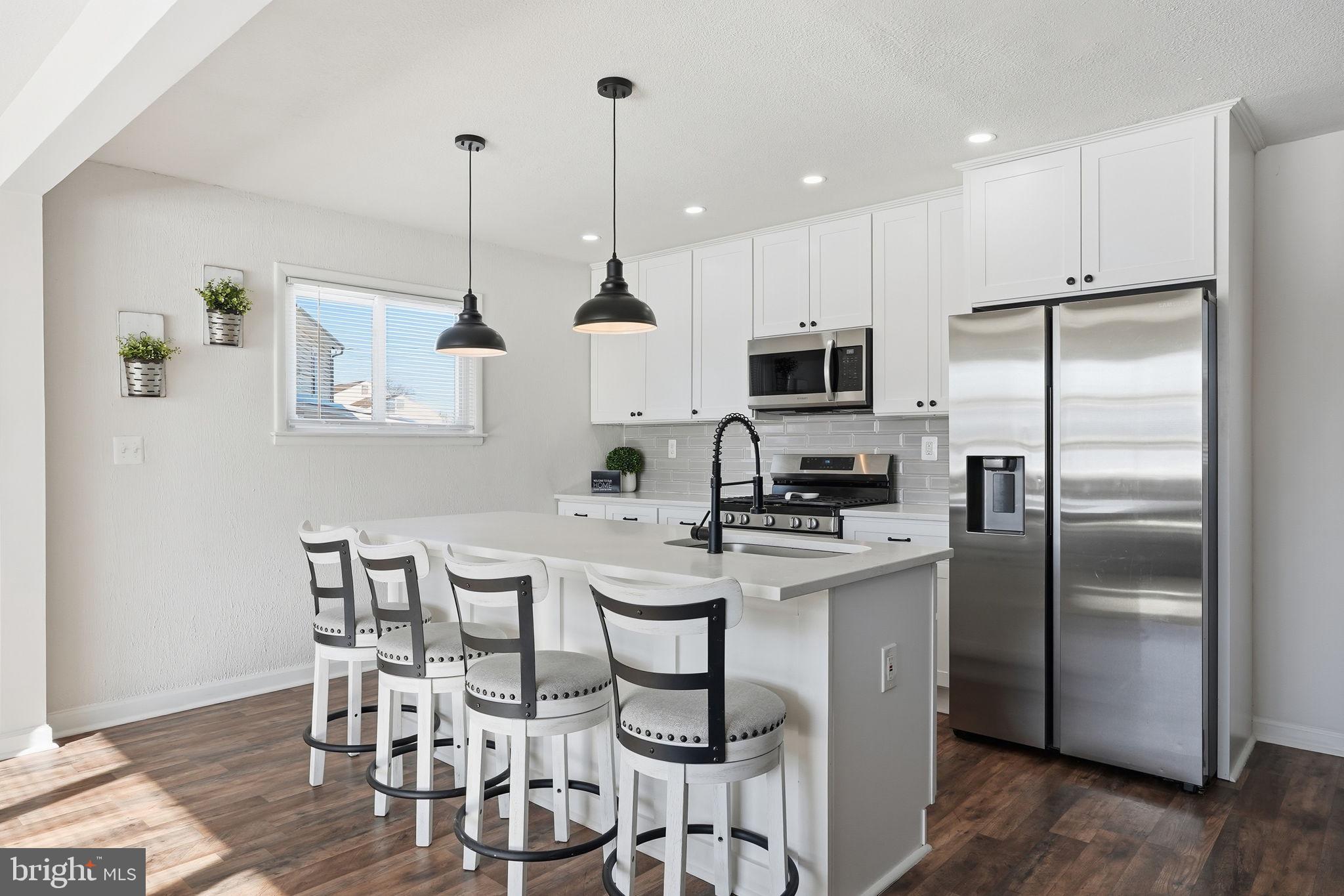 105 Michael Avenue Linthicum Heights, MD 21090 - Photo 7 of 24 a kitchen with stainless steel appliances kitchen island a table chairs refrigerator and microwave