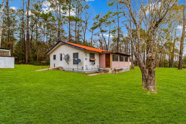 a view of a house with a big yard and large trees