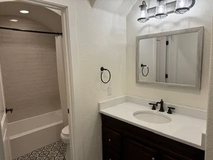 a bathroom with a granite countertop sink a toilet and shower