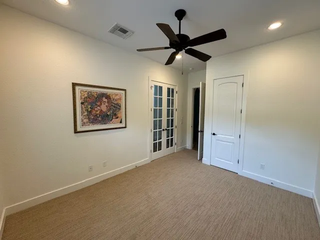 a view of a livingroom with a ceiling fan & windows
