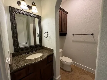 a bathroom with a granite countertop sink toilet and mirror