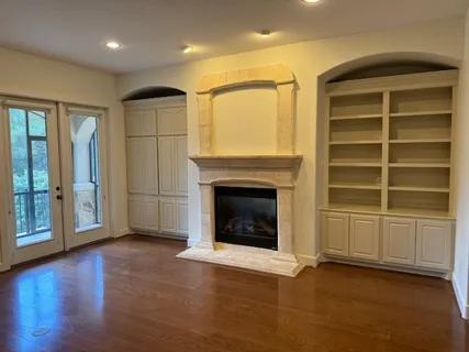 an empty room with a fireplace wooden floor and windows