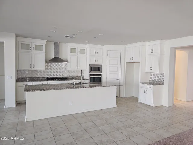 a kitchen with granite countertop white cabinets and stainless steel appliances