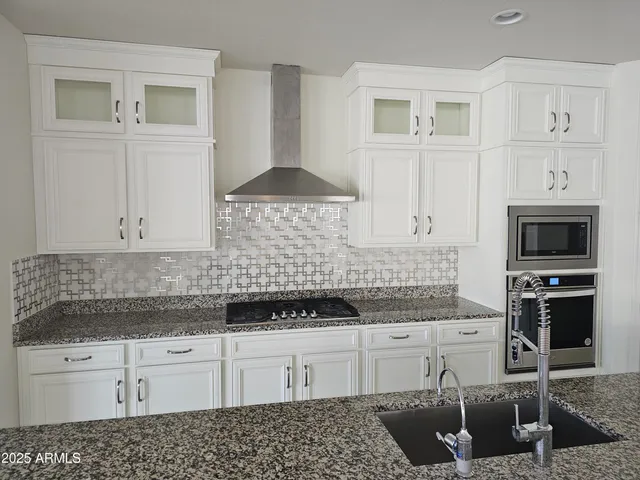 a kitchen with granite countertop white cabinets and stainless steel appliances