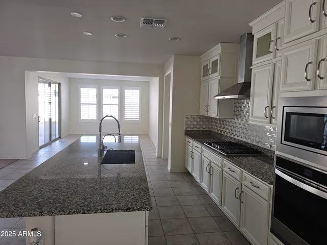 a kitchen with stainless steel appliances granite countertop a sink a stove and cabinets