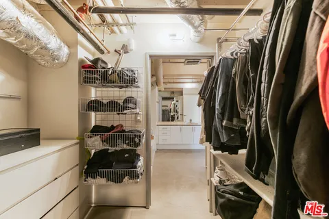 a view of walk in closet with clothes and shoes