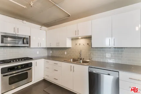 a kitchen with white cabinets stainless steel appliances and sink