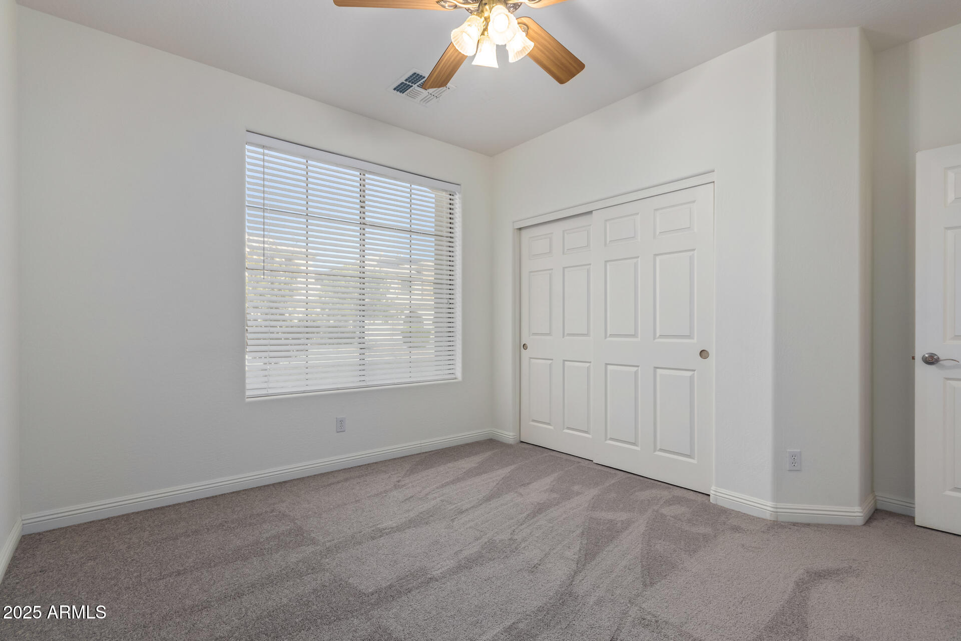 13635 West Calavar Road Surprise, AZ 85379 - Photo 65 of 76 an empty room with chandelier fan and windows