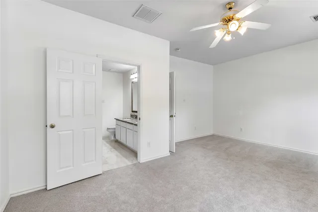 an empty room with chandelier fan and windows