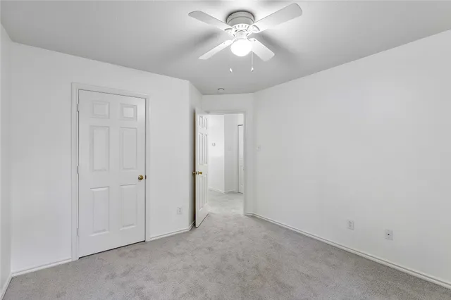 an empty room with a ceiling fan and a fan