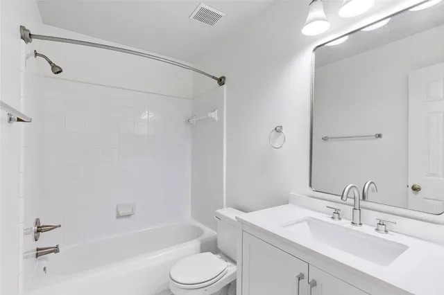 a bathroom with a bathtub shower sink vanity mirror and toilet