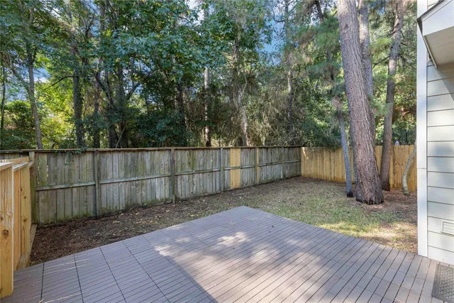 a view of a backyard with wooden fence and large trees