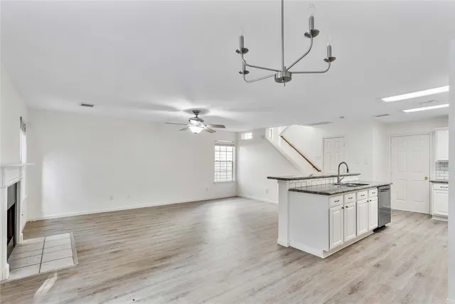 a view of a room with wooden floor ceiling fan and windows