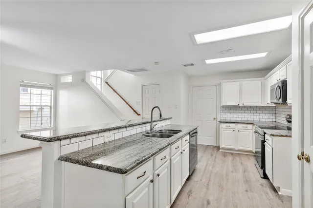 a kitchen with granite countertop a sink stove and cabinets