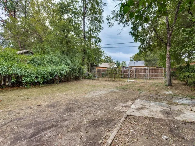 a backyard of a house with large trees and outdoor seating
