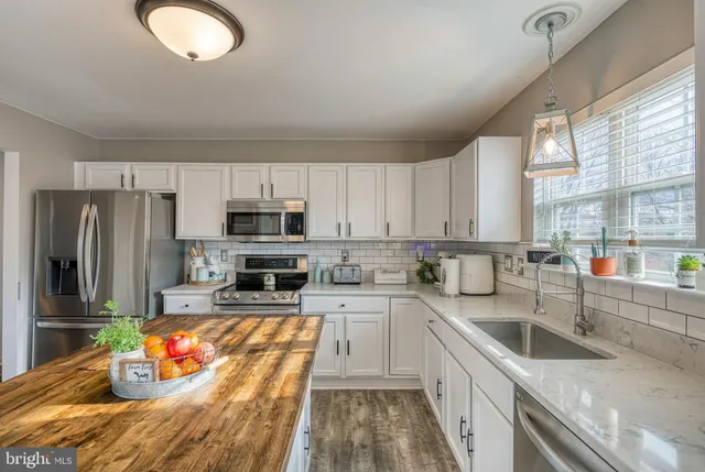 a kitchen with stainless steel appliances granite countertop a sink window and cabinets