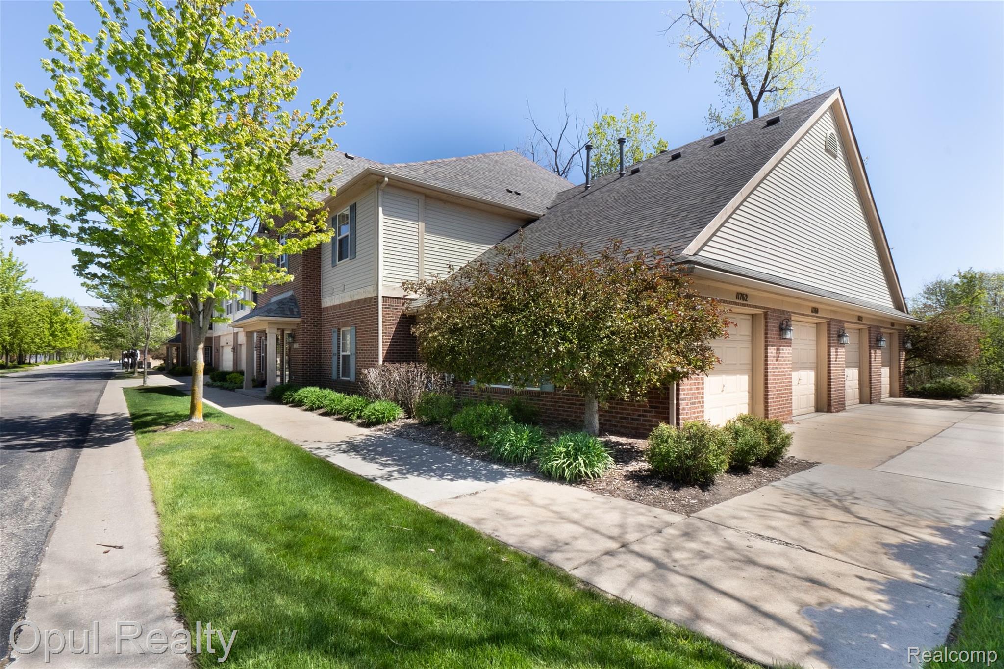 11762 Farmington Road Livonia, MI 48150 - Photo 21 of 25 View of property exterior with brick siding, driveway, a garage, roof with shingles, and a lawn