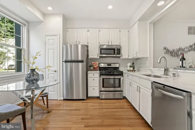 a kitchen with kitchen island white cabinets and stainless steel appliances