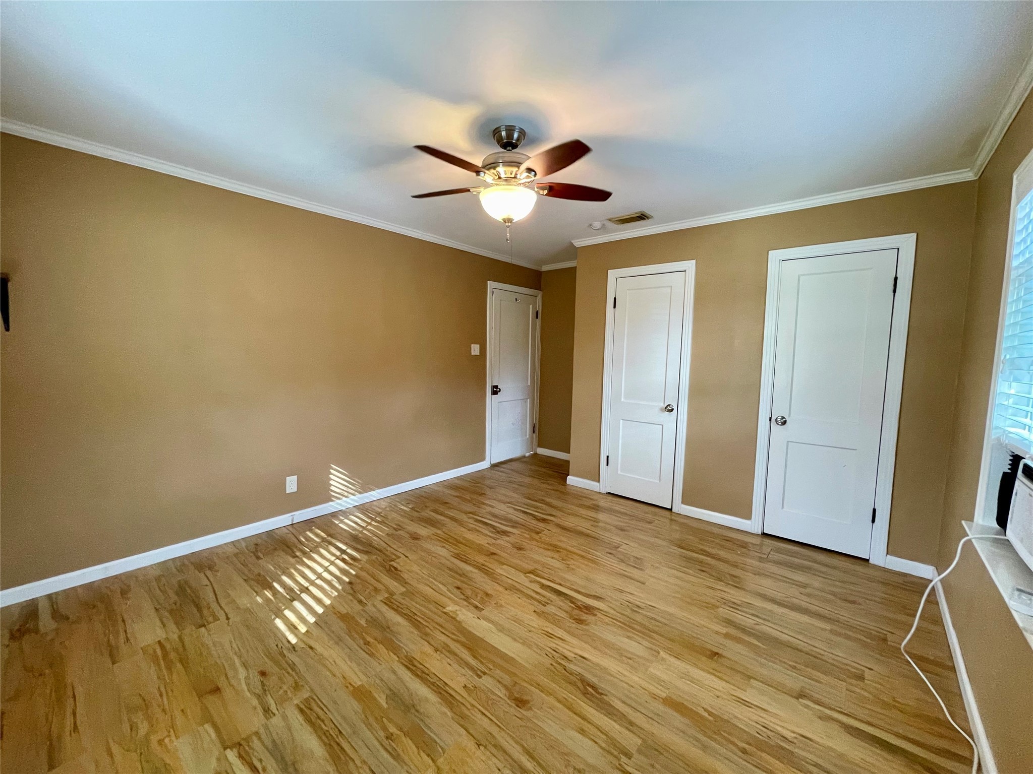 1113 Chevy Chase Drive Angleton, TX 77515 - Photo 18 of 32 a view of an empty room with wooden floor and a ceiling fan