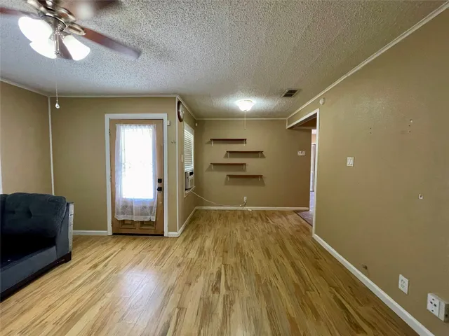 a view of empty room with wooden floor and fan