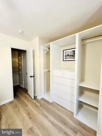 a view of a hallway with wooden floor and a bathroom
