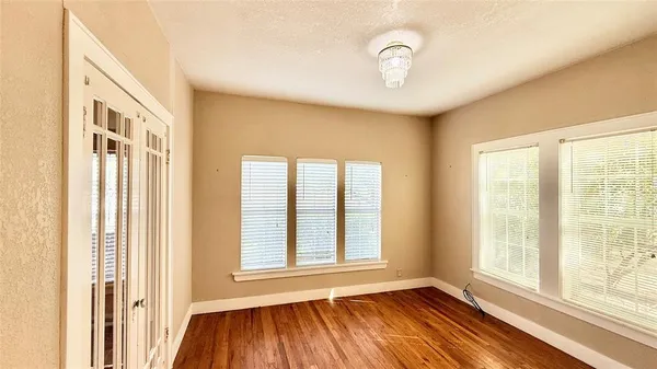 a view of an empty room with a window and wooden floor
